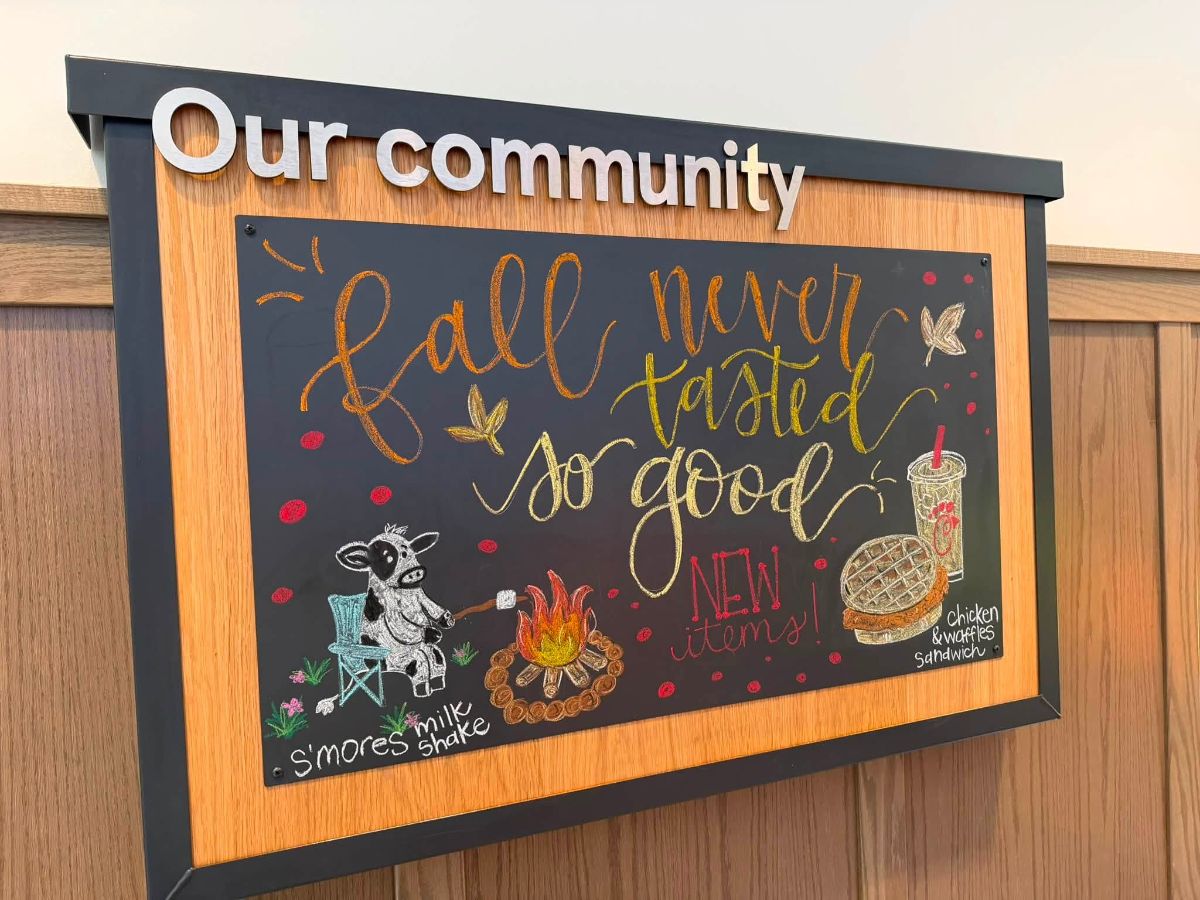Hand lettered chalkboard art for a restaurant community board: fall never tasted so good in orange and gold brush script, a cow roasting a marshmallow over a campfire for a s'mores milkshake, and a chicken and waffles sandwich